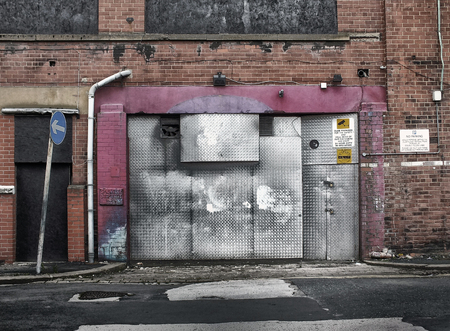 derelict abandoned commercial property awaiting demolition or redevelopment with boarded up entrance and decaying brickwork in an empty roadの写真素材
