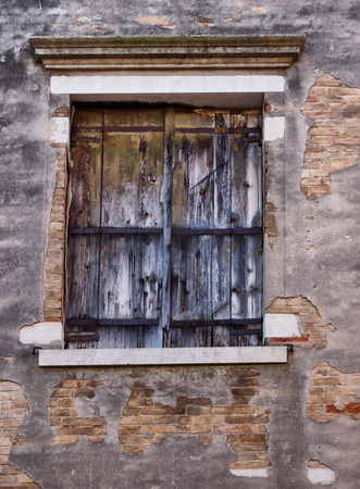 old wooden shuttered window with faded peeling black paint in an ancient brick wall with peeling broken grey cement or plasterのeditorial素材
