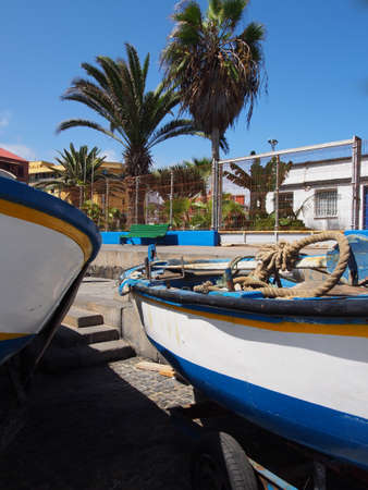 two small fishing boats on the harbor at puerto de la cruz tenerife with dockside rope palm trees and blue skyの写真素材