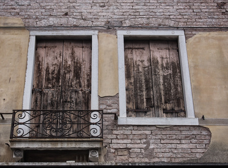 house detail with shutters on windows in venice balcony cracked plaster yellow wall and elegant...