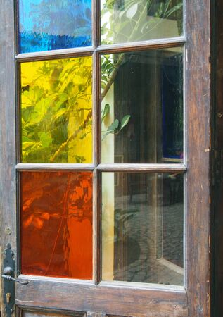 Coloured glass panes in an old wooden door opening on to a gardenの写真素材