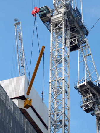 detail of a large construction crane lifting a large metal beam and bucket の写真素材