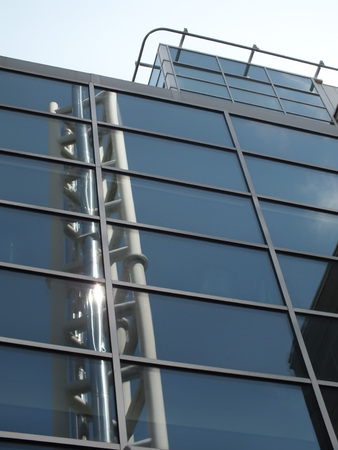steel industrial tower reflected in the glass windows of a modern industrial building with sunlight...