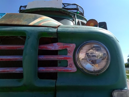 front headlamp and grill or an old rusty bus with green hood luggage rack on the roof and blank destination boardの写真素材