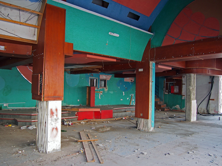 the interior of a derelict abandoned discotheque or nightclub with rubble covered floor and wired hanging from many coloured painted walls and a rubbish covered stageの写真素材