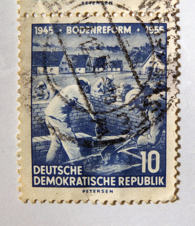 Leeds, England - April 18 2018: An old blue east german postage stamp with building workers on a construction siteのeditorial素材