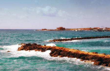 summer view of the harbour in puerto de la cruz spain with bright blue sea and waves breaking on the harbour wall with the historic castle and moored boats visible in the distanceの写真素材