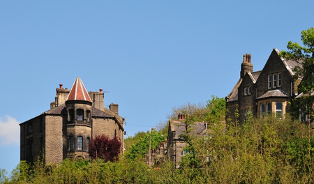 Tall stone gothic houses set in the woodland landscape in Hebden bridge west Yorkshire with blue skyの写真素材