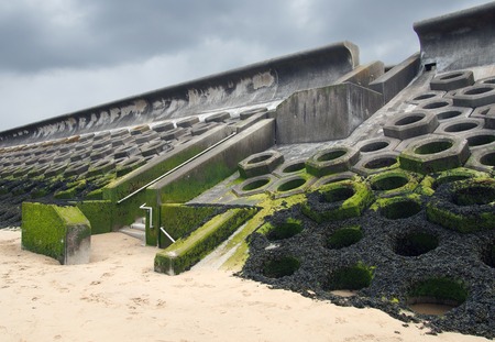 the seawall south of blackpool constructed of concrete honeycomb type structures with steps leading to the beach covered in tidal seaweedの写真素材