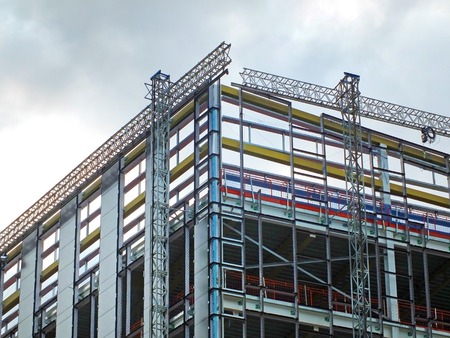 a large modern building site with construction scaffolding and steel girder framework with safety...