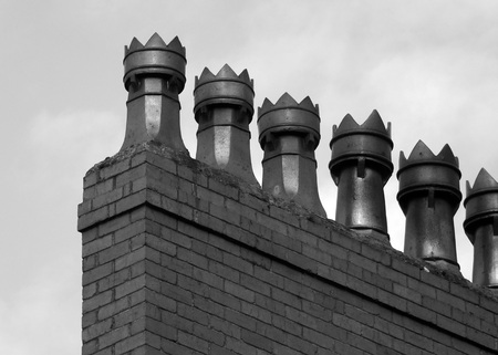 monochrome image of a row old fashioned chimney pots on a brick built houseの写真素材