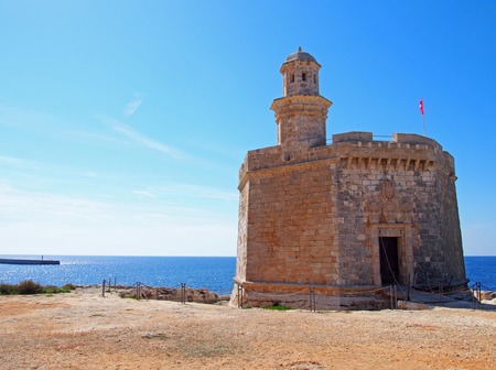 The Sant Nicolau Castle in ciutadella menorca on the cliffs with blue summer sea and blue skyのeditorial素材