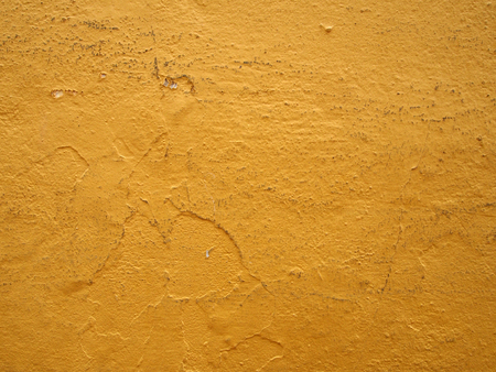 Bright yellow dirty painted cracked old wall texture backgroundの写真素材