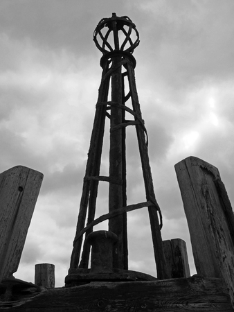 A monochrome image of the ruined beacon towers on the derelict wooden mooring jetty at lytham saint annes against a cloudy skyの写真素材
