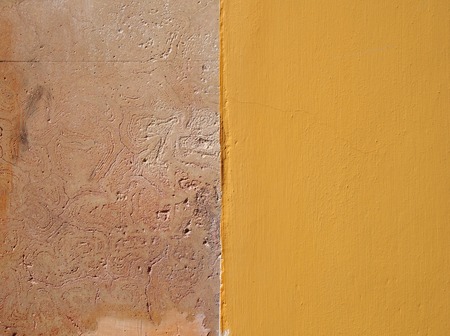 a beige textured limestone wall surface half painted in bright yellowの写真素材