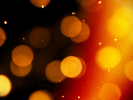 golden orange glow on a black background with round blurred lights and bright yellow sparkles