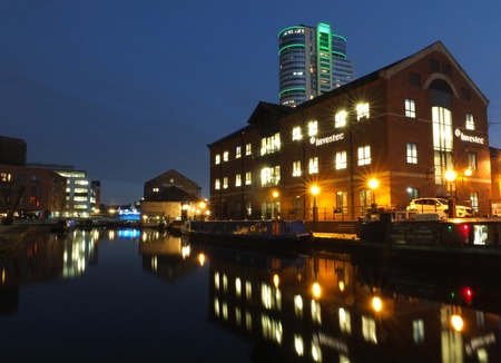 Leeds, England - 24 January 2019: a view of the canal in leeds at night showing businesses reflected in the water and bridgewater place in the distanceのeditorial素材