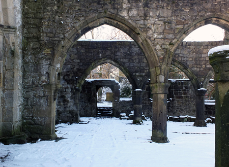arches and columns in the ruined medieval church in hebden bridge west yorkshire with snow covering the ground in winterの写真素材