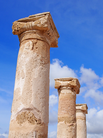 old roman columns in sunlight against a blue summer sky with clouds in kato park paphos cyprusの写真素材