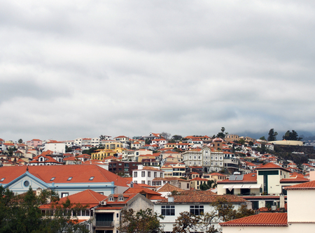 a panoramic cityscape view of funchal showing roofs and buildings of the town cente and cloudy skyの写真素材
