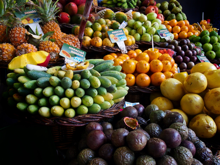 a display of colorful tropical fruit on sale on a market stall in funchal madeira signs read forest plum tomato orange passionfruit pineapple and banana passionfruitの写真素材