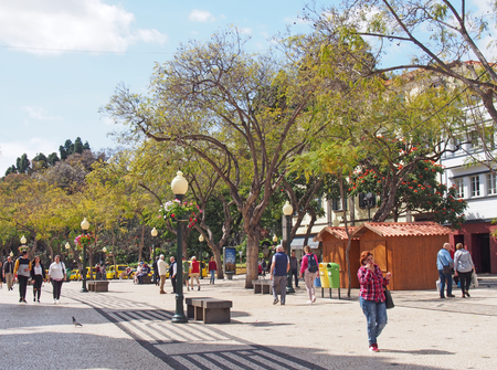 funchal, madeira, portugal - 14 march 2019: people walking down a main pedestrian street next to the public park in funchal madeira in bright sunlightのeditorial素材