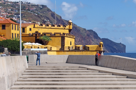 funchal, madeira, portugal - 15 march 2019: tourists take photos and look at the view by the sea outside the yellow fort in funchal madeira in bright sunshineのeditorial素材