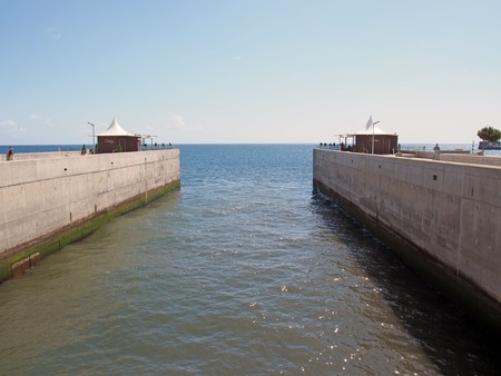 Funchal, madeira, portugal - 17 march 2019: people relaxing on the concrete piers on the river in funchal exiting into the seaのeditorial素材