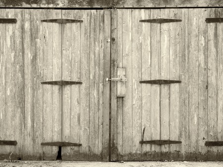 Monochrome old rural grey plank wooden plank doors with a bolt fastening and rusty iron hingesの写真素材