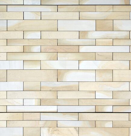 full frame image of a wall made of large flat blocks of textured yellow light brown york stone in...