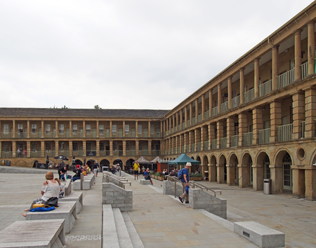 halifax, west yorkshire, united kingdom - 12 july 2019: people sat on the steps of the piece hall in halifax west yorkshire with people shopping and sat in cafes and barsのeditorial素材