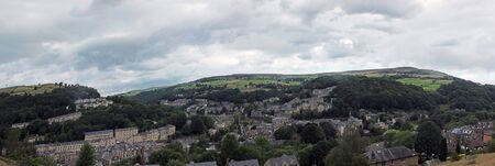 a wide panoramic view of the town of hebden bridge with hillside streets surrounded by trees and...