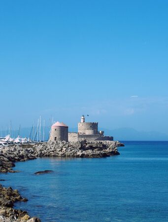 boats moored near the tower and fort of saint nicholas on the old harbour in rhodes town