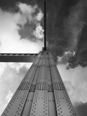 dramatic monochrome perspective view of the support of a tall old steel suspension bridge with rows...