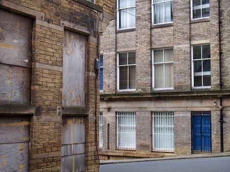 a street corner view of closed and boarded up old abandoned industrial and office buildings in the...