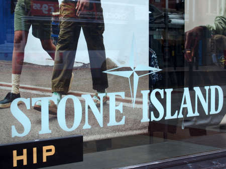 leeds, west yorkshire, united kingdom - 11 may 2021: stone island logo and posters in the window of...