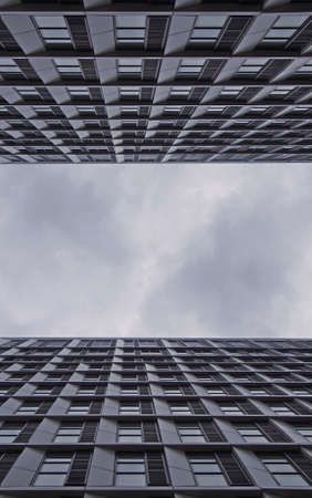 cloudy sky between two tall modern apartment buildings with repeating geometric windows