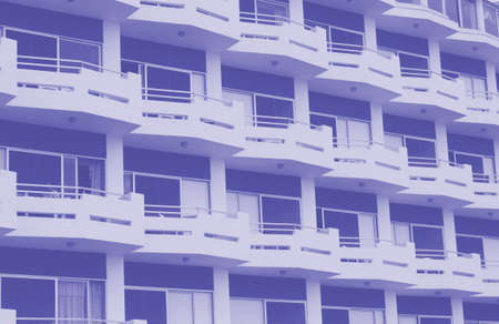 blue duotone image of modern apartment buildings with white balconies and blue details with angular...