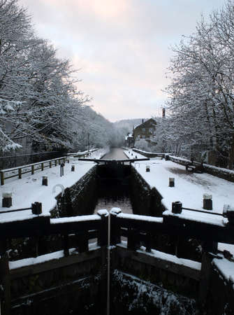 winter scene on the rochdale canal in hebden bridge with snow covered towpath and housesの写真素材