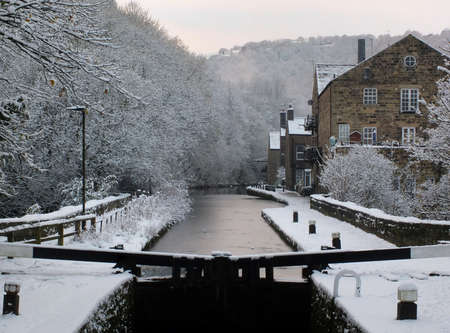 winter scene on the rochdale canal in hebden bridge with snow covered towpath and housesの写真素材