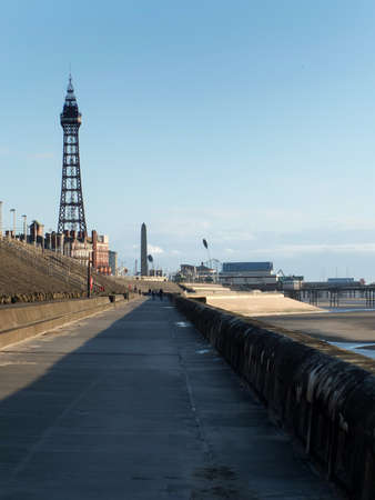 view of blackpool tower and south pier from the promenade with town buildings in afternoon sunlightの写真素材