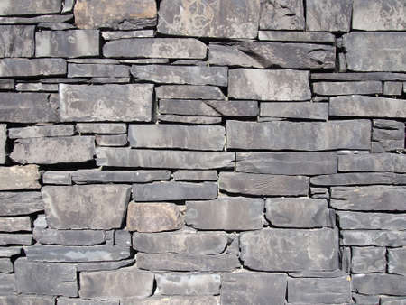 old grey slate stone wall with irregular shaped slabsの写真素材