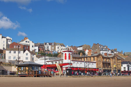 Scarborough, North Yorkshire, United Kingdom - 12 September 2022 : buildings along the seafront at scarborough south bay with the coney island amusement arcade and tourists near the beach on a sunny summer dayのeditorial素材