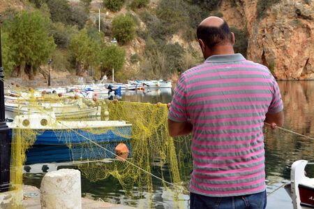 Repair of fishing net in a Greek port.の写真素材