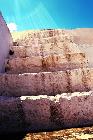 An old staircase in stones with rays of sunshine.