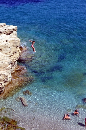 Girl who jumps since a cliff into the transparent sea.
