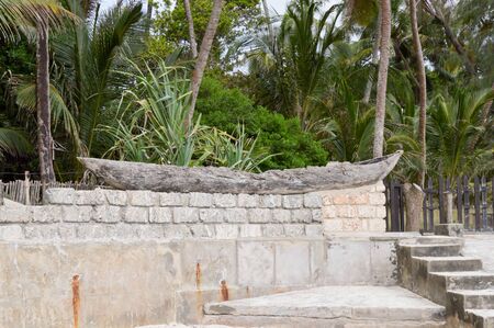 Old wooden canoe posing on a low wall separating Bamburi beach in Kenya from holiday makersの写真素材