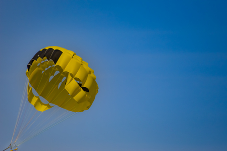 Black and yellow parachute on a blue sky backgroundの写真素材