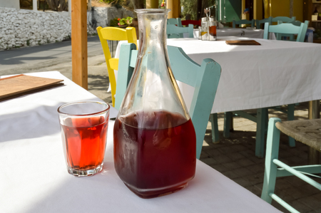 Carafe red wine and a glass filled on a table of a resturant in the center of the island of Creteの写真素材