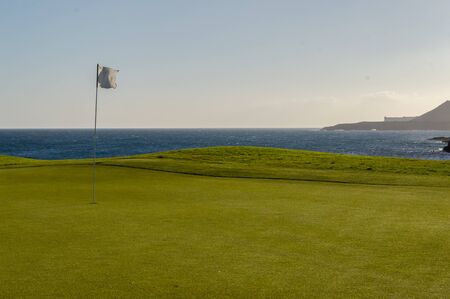 Green golf with flag and hole facing Atlantico ocean in Santa Cruz de Tenerifeの写真素材